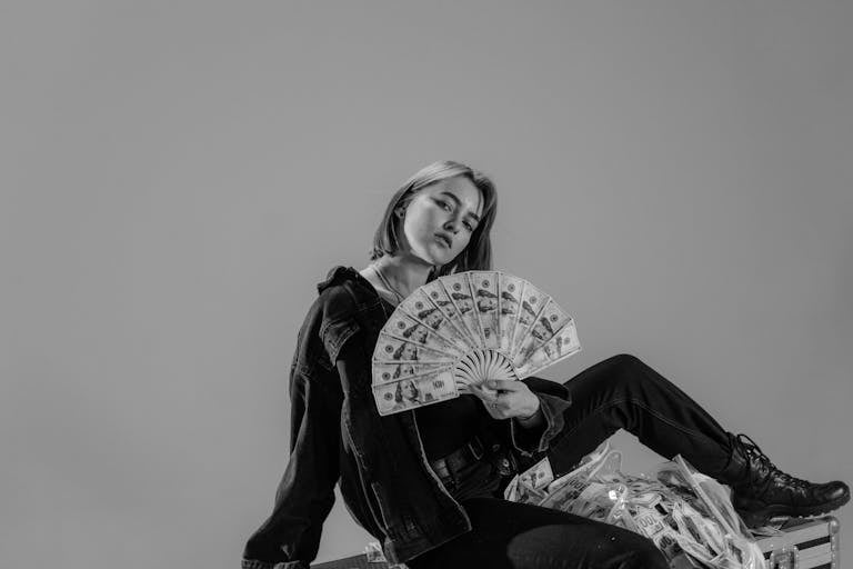 Stylish young woman holding a fan of cash, exuding a confident, modern vibe.