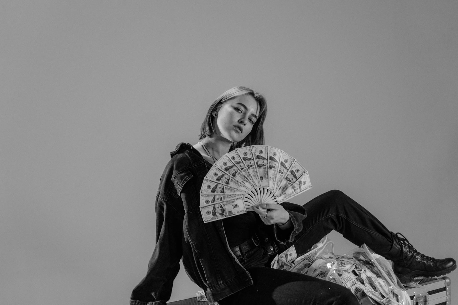 Stylish young woman holding a fan of cash, exuding a confident, modern vibe.